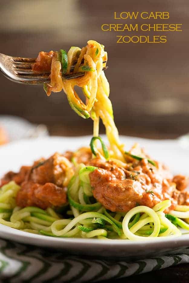 A fork twirling up some spaghetti above a plate.