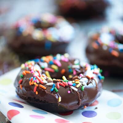 a chocolate donut with sprinkles on a polka dot plate