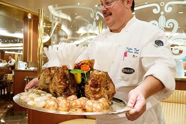 A man holding a plate of food, with veal.