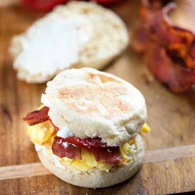 A BLT on an English muffin on a wooden cutting board