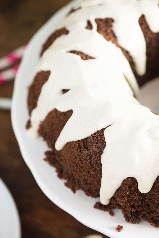 White icing on a chocolate pound cake placed on a cake stand.