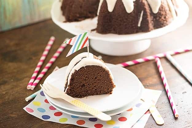 A slice of pound cake on a white plate with a cake stand in the background.