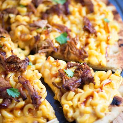 Macaroni and cheese and pulled pork pizza on a pizza pan.