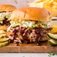 Slow cooker pulled pork made in the crock pot! Perfect for these easy sandwiches with dill pickle slaw and homemade barbecue sauce! This is one of our favorite recipes!