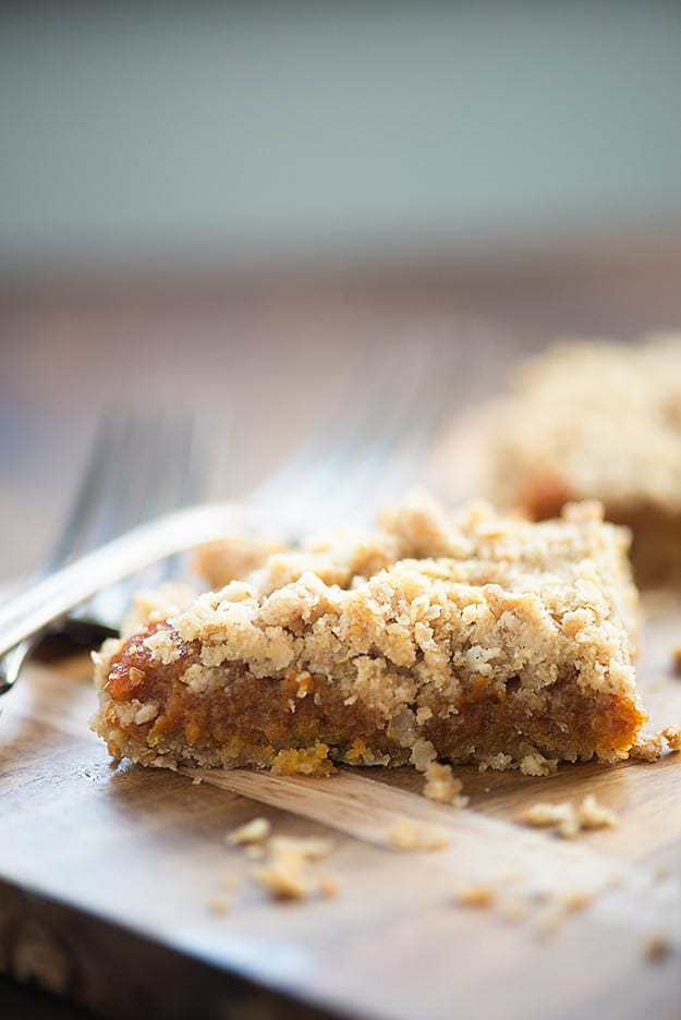 Close up of a pumpkin oatmeal bar on a wooden cutting board.