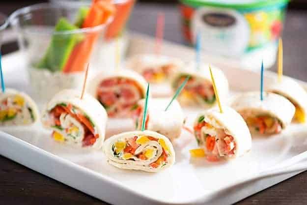 An appetizer tray full of vegetable roll-ups with toothpicks going through them.