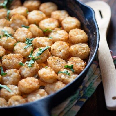 A tater tot casserole in a cast-iron skillet on a folded cloth napkin.