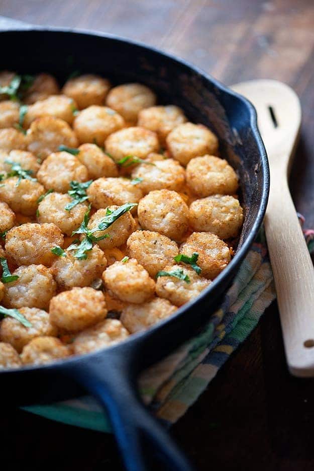 A tater tot casserole in a cast-iron skillet on a folded cloth napkin.