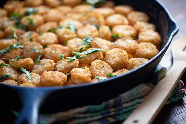 A tater tot casserole in a black cast-iron skillet.