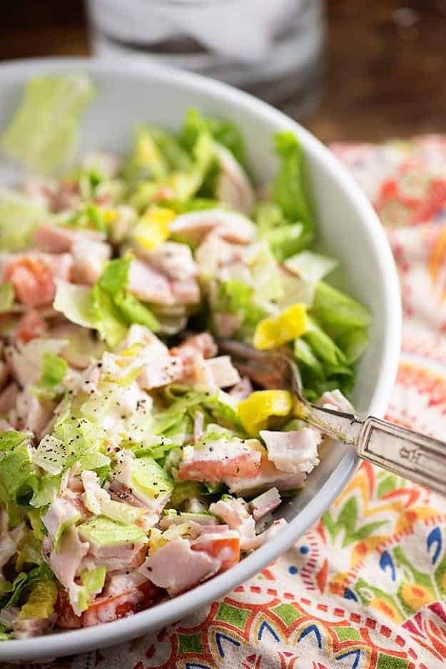 An overhead view of a silver fork going into a chopped salad.