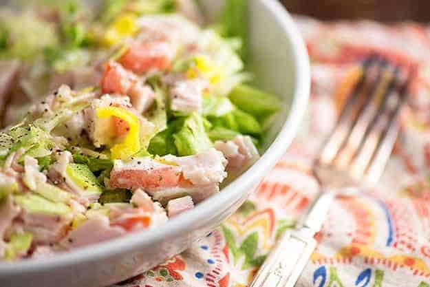 A close up of a bowl of salad next to a cloth napkin.