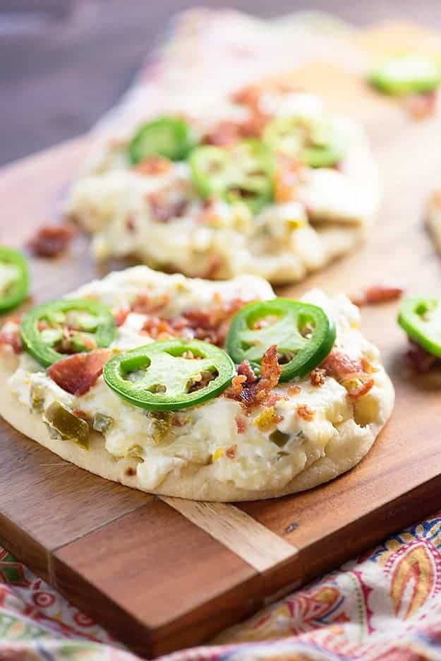 A wooden cutting board with several jalapeno flatbreads on it.