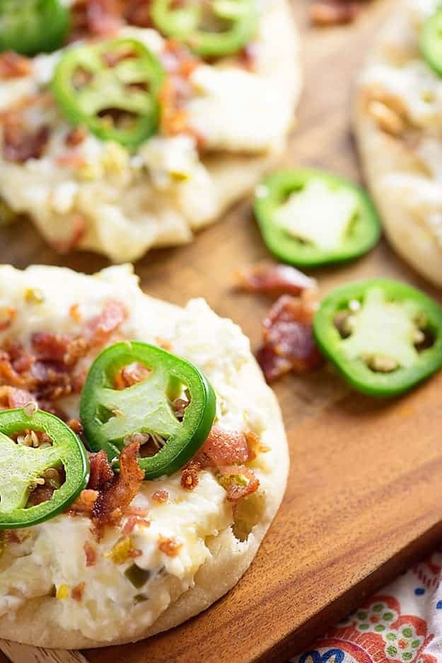 Jalapenos spread throughout a cutting board full of jalapeno popper flatbread.