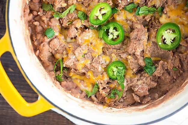 A large pot full of refried beans with jalapenos.