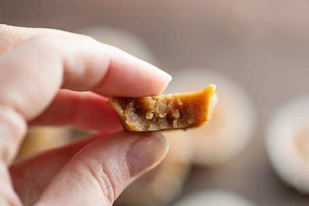 A woman holding up a piece of fudge with a bite taken out of it.