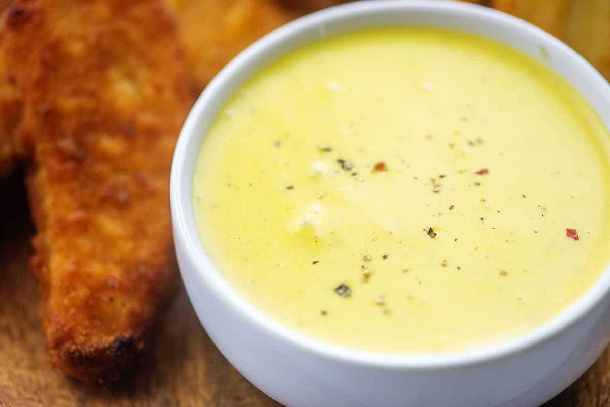 honey mustard sauce in white bowl surrounded by chicken strips