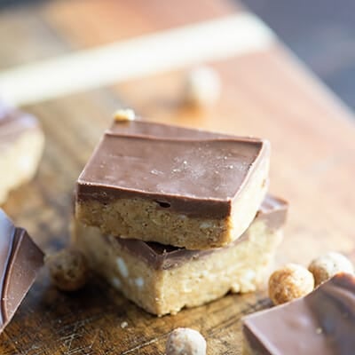 Two stacked up peanut butter bars with chocolate icing.