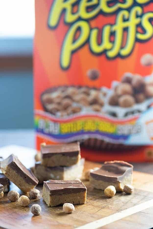 Several peanut butter bars in front of a box of cereal.