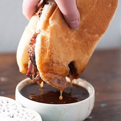 slow cooker french dip sandwich being dunked in au jus