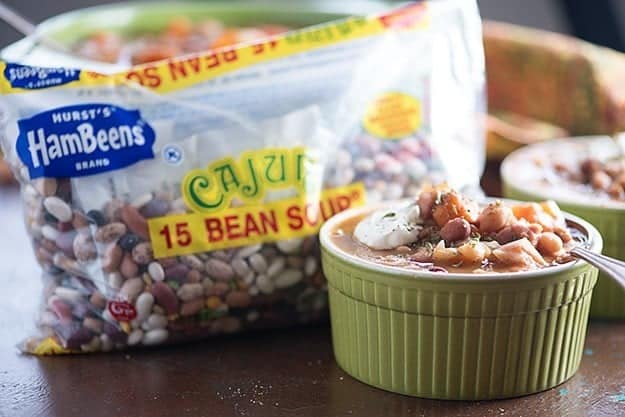 A bowl of soup in front of a bag of cajun beans.