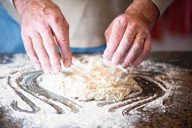 man working flour into biscuit dough.