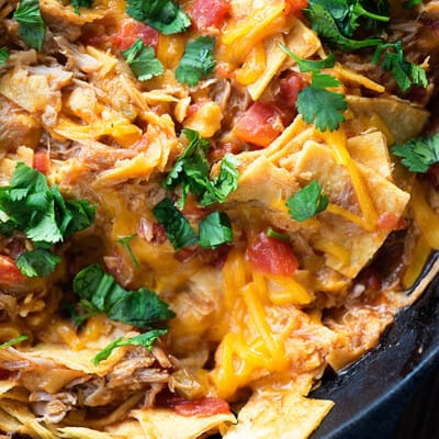 A close up of pulled pork and melted cheese in a cast-iron skillet.