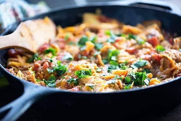 A cast iron skillet with cheese and pork in it.