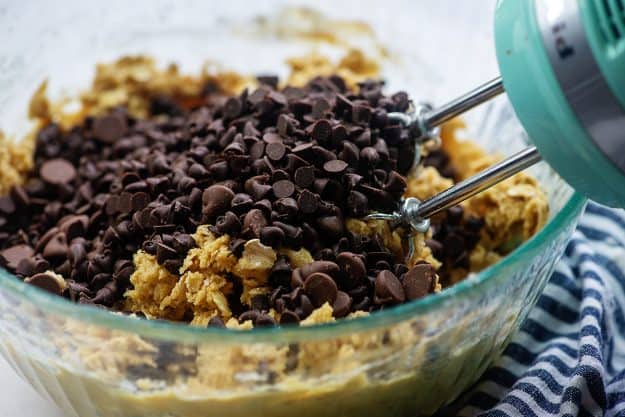 chocolate chips over cookie dough in glass mixing  bowl