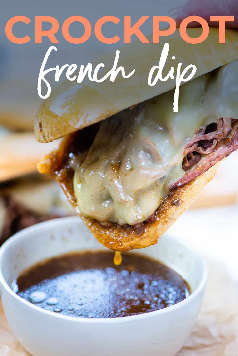 French dip sandwich being dunked in au jus.