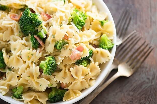 Brocolli and bowtie pasta in a white bowl.