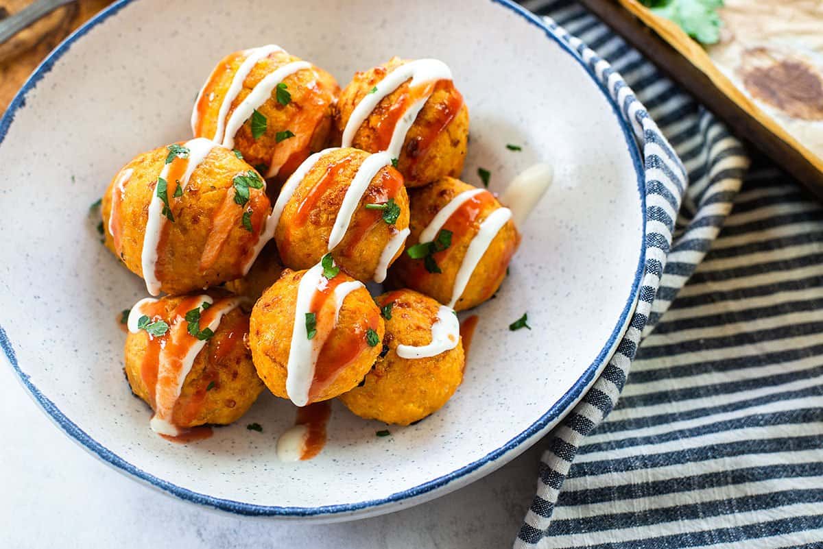 meatballs topped with hot sauce and ranch in bowl.