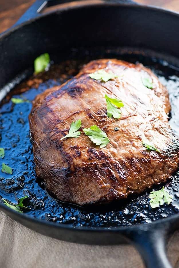 Flank steak in a cast-iron skillet.