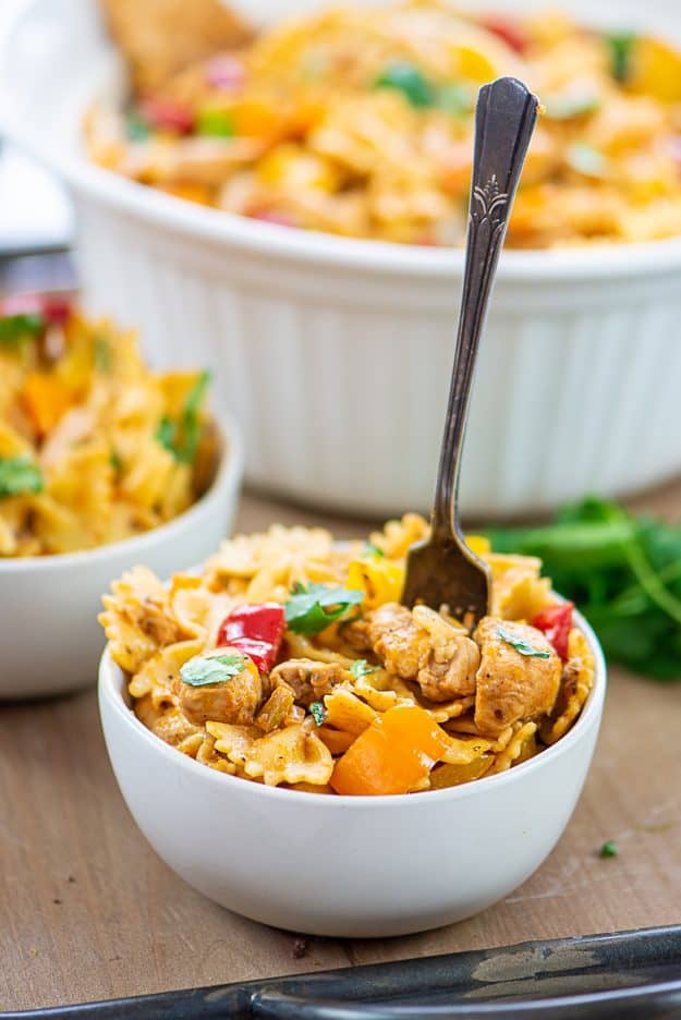 pasta with chunks of chicken and vegetables in white bowl with vintage fork.