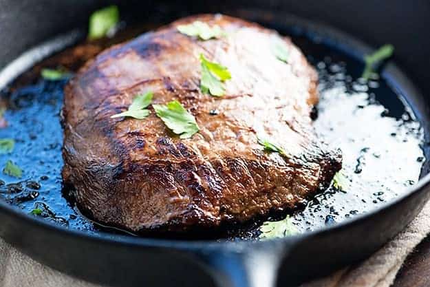Seasoned flank steak in a cast-iron skillet.