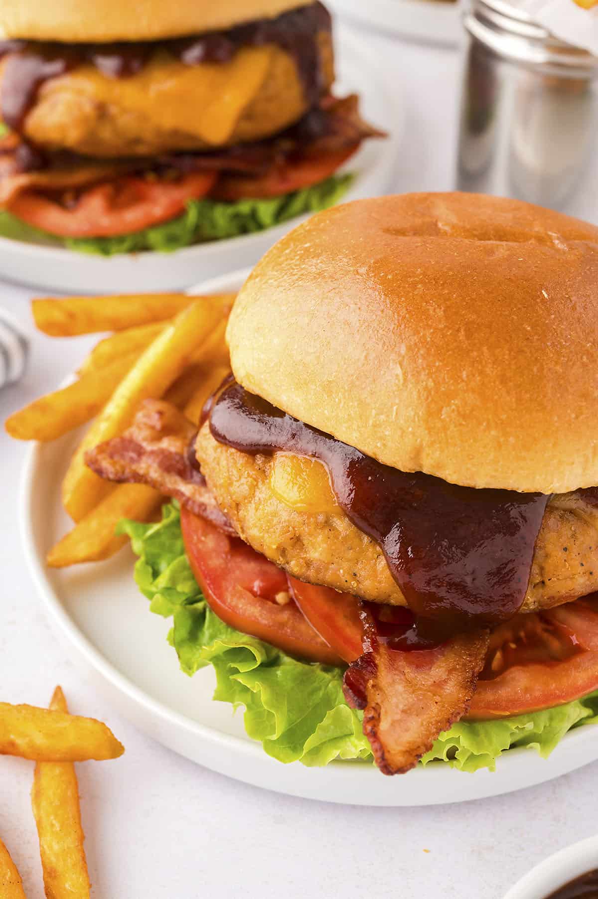 Chicken burger with barbecue sauce and bacon on bun.