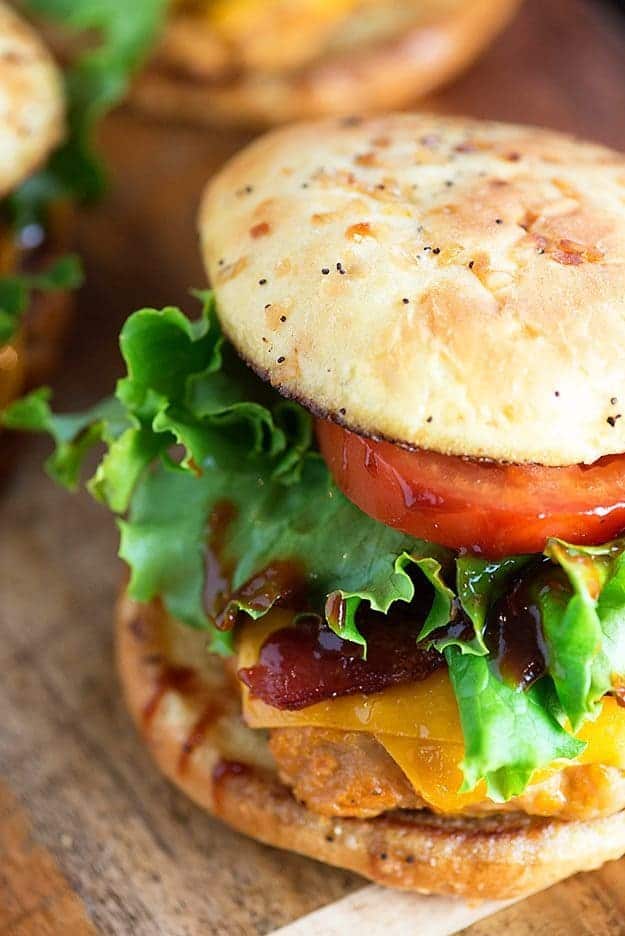 A top-down view of a chicken burger topped with tomato and lettuce.