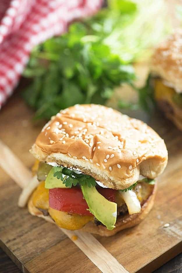 I topped these steak fajita burgers with cheddar, avocado, cilantro, and sour cream! Don't forget the grilled peppers and onions!