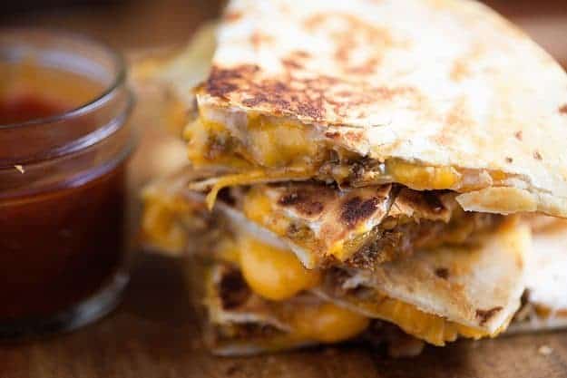 A stack of quesadillas on a wooden cutting board.