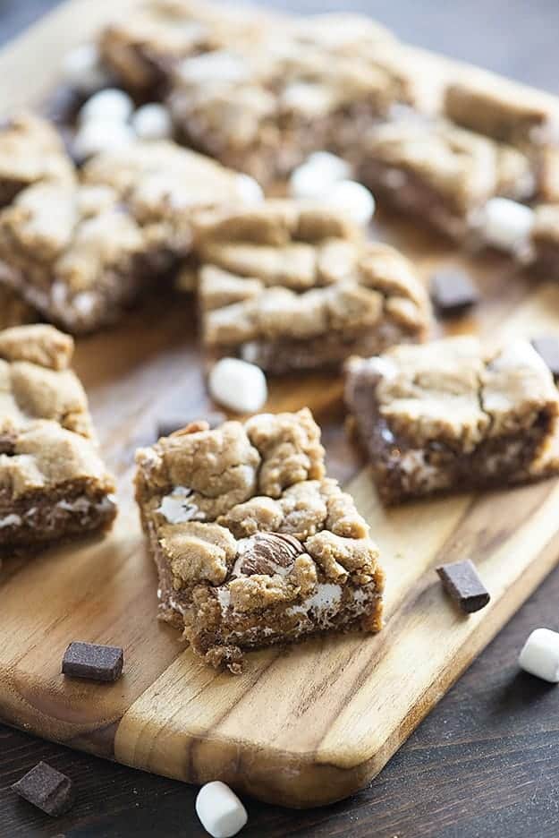 Several squares of smores bars on a thin wooden cutting board.