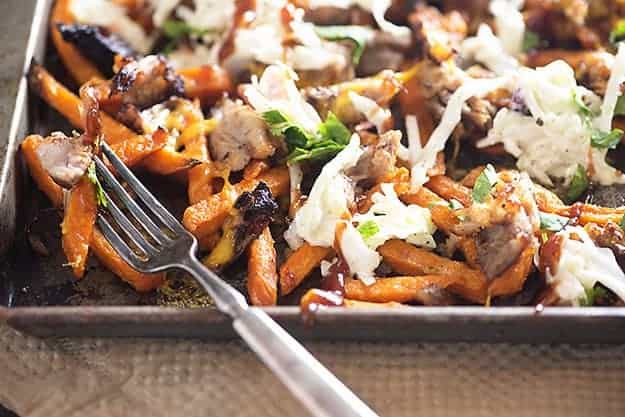 A baking sheet of sweet potato fries topped with pulled pork and cole slaw.