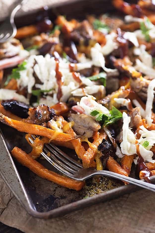 A close up of a baking sheet of loaded sweet potato fries.