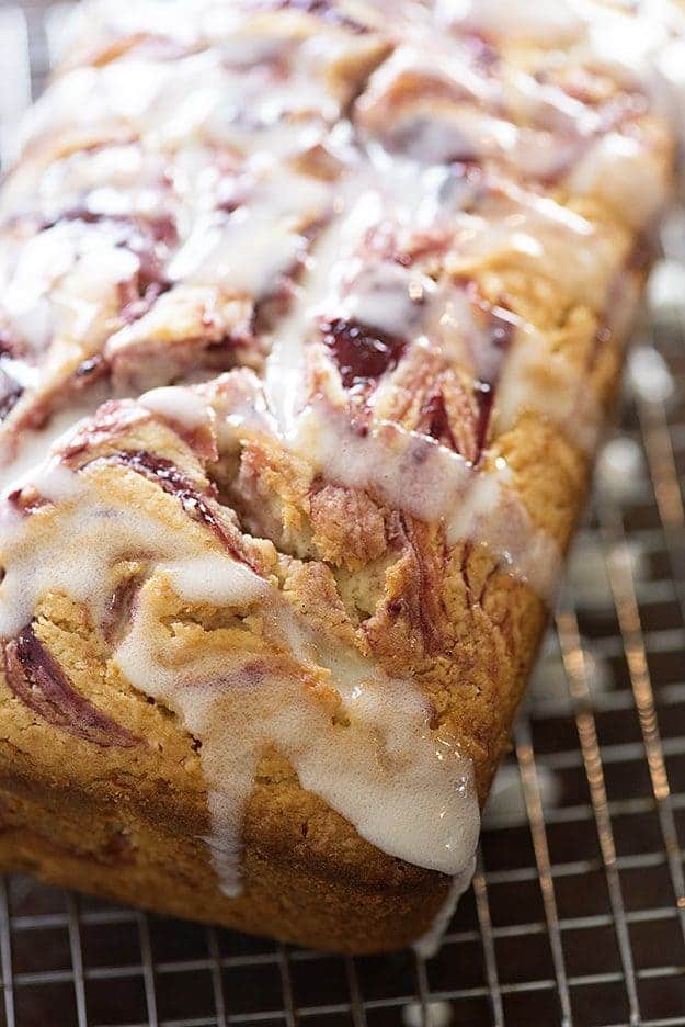 A close up of raspberry muffin bread topped with white icing.