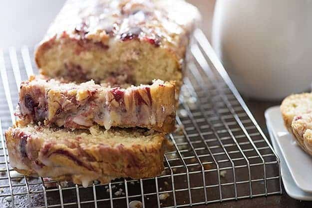 A sliced loaf of raspberry bread loaf on a wire cooling rack.