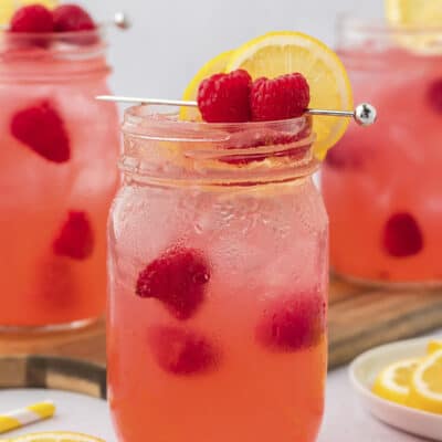 Cocktail made with vodka and raspberries in glass mason jar.