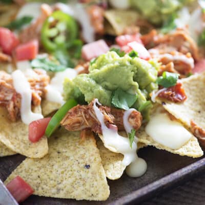 These sheet pan nachos are topped with slow cooker shredded chicken and the easiest white queso you'll ever make!