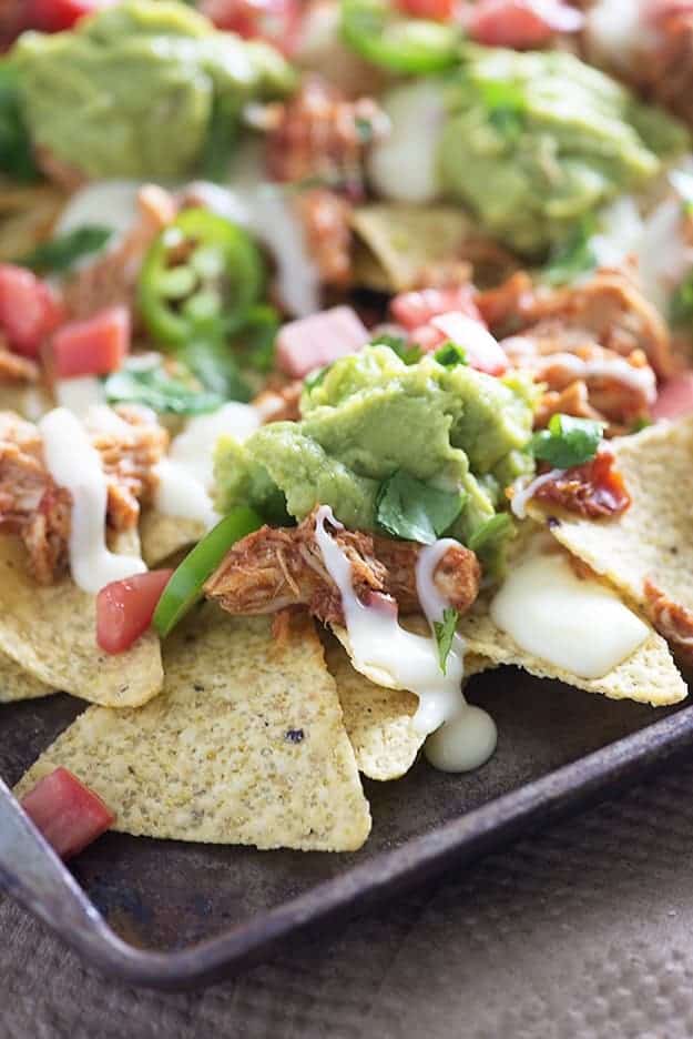 These sheet pan nachos are topped with slow cooker shredded chicken and the easiest white queso you'll ever make!