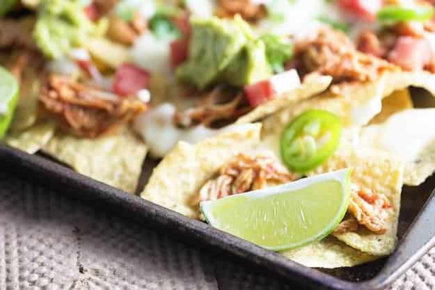 These sheet pan nachos are topped with slow cooker shredded chicken and the easiest white queso you'll ever make!