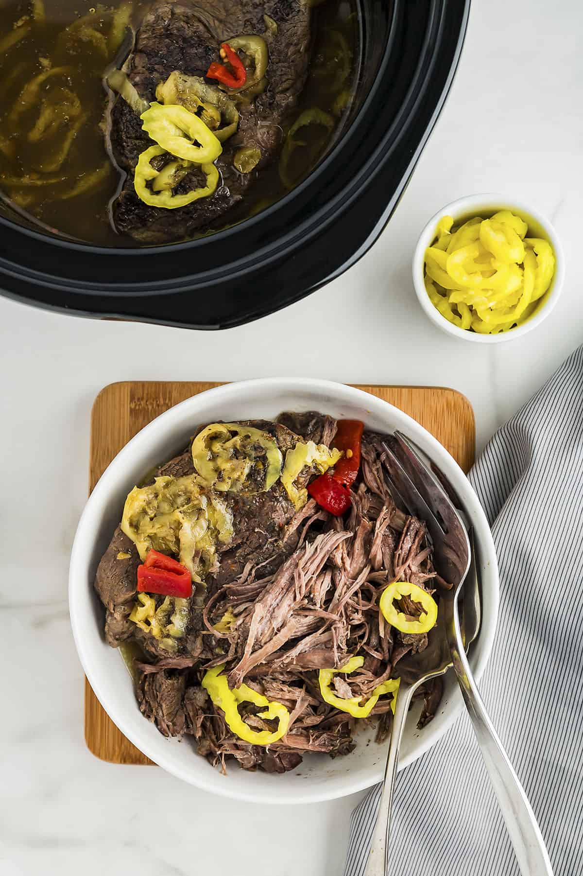 Beef being shredded in small bowl.