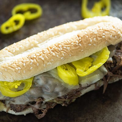 A close up of an Italian beef sandwich on a sesame seed hoagie bun.