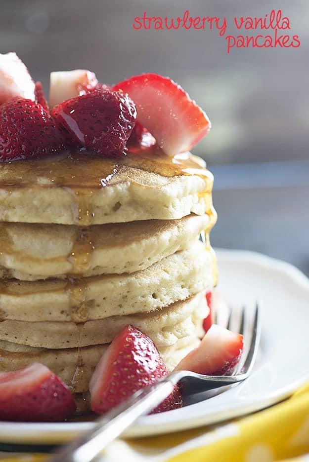 A stack of pancakes topped with strawberries and syrup.